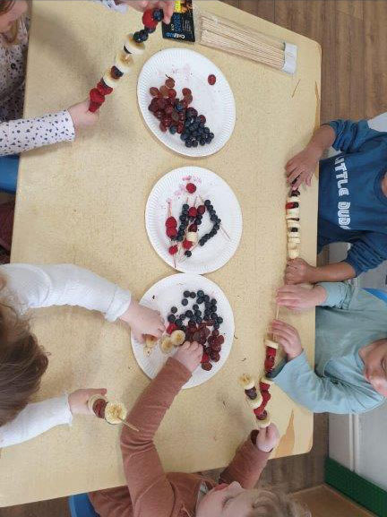 Children threading grapes, berries and banana onto skewers